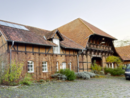 Eingangsbereich eines historischen Bauernhauses in Isernhagen mit Fachwerk, Ziegelmauerwerk und traditioneller Dachkonstruktion.