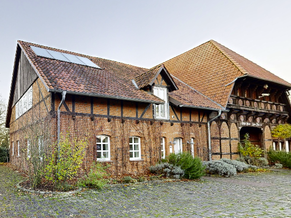 Eingangsbereich eines historischen Bauernhauses in Isernhagen mit Fachwerk, Ziegelmauerwerk und traditioneller Dachkonstruktion.